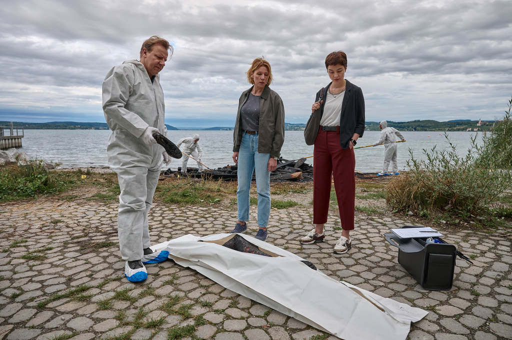 Gerichtsmediziner Gregor Eisen (Ronald Kukulies, l.) gibt den Kriminalkommissarinnen Doro Beitinger (Franziska Weisz, M.) und Chiara Locatelli (Maria Wördemann, r.) am Tatort am Ufer des Bodensees erste Informationen zum brisanten Todesfall.